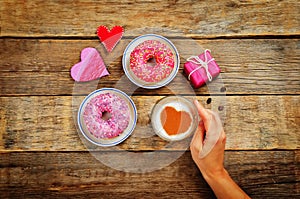 Wood background with cup of coffee, donuts, gift, hearts and wom