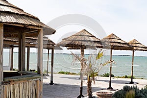 Wood bamboo hut as a bar straw roof on beach and many straw parasol in panoramic view