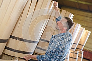 Wood barrels production cooper using hammer and tools in workshop