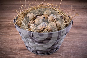 Wood basket filled with eggs of quails on wooden background
