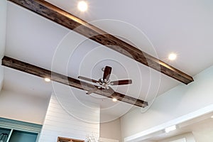 Wood beams and recessed bulbs with ceiling fan and lights at the center