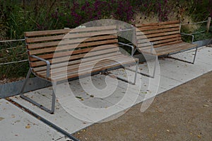 Wood benches on their paneling under the benches is a rectangle of concrete anti-scraping beige paths by the shoes of visitors flo