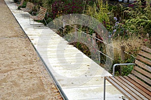 Wood benches on their paneling under the benches is a rectangle of concrete anti-scraping beige paths by the shoes of visitors flo