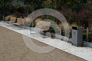 Wood benches on their paneling under the benches is a rectangle of concrete anti-scraping beige paths by the shoes of visitors flo