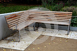 Wood benches on their paneling under the benches is a rectangle of concrete anti-scraping beige paths by the shoes of visitors flo