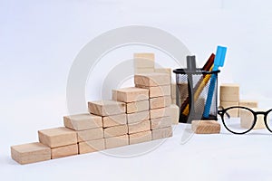Wood block stacking as step stair on wooden table. Business concept for growth success process with color marker case and glasses