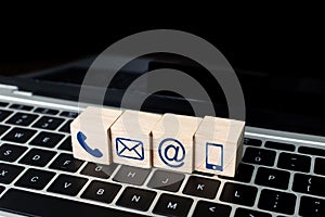 Wood block symbol telephone, mail, address and mobile phone on laptop keyboard. Website page contact us