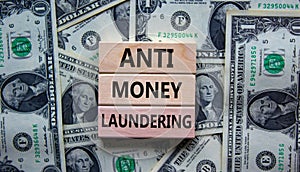 Wood blocks with words `Antimoney laundering` on a beautiful background from dollar bills. Business concept, copy space