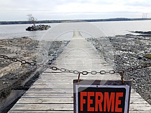 Wood boardwalk or pier with ferme or closed in French sign
