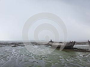 Wood boat beached at the low tide time on the bay in the rainny day