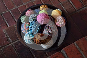 Wood bowl filled with colorful balls of hand spun wool yarn