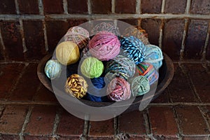 Wood bowl filled with colorful balls of hand spun wool yarn