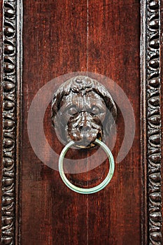 Wood carved lion head with metal ring as door knocker