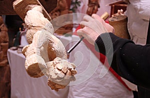 Wood carver's hands sculpting a wooden angel