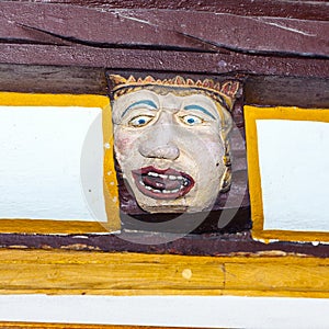 Wood carving with funny face on timber balk