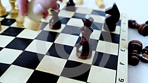 Wood chessboard during game. Knight's move. Female hand making checkmate.