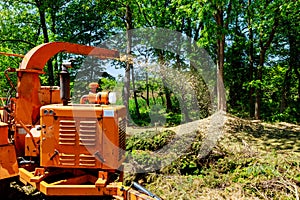 Wood Chipper in Action captures a wood chipper or mulcher shooting chips over a fence.
