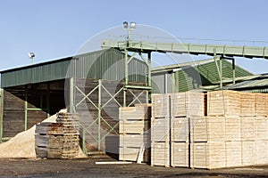 Wood chips pellets chopped wooden logs and stacked wooden pallets for biomass fuel at sawmill