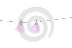 Wood clothes pins with two blank pink paper in heart shaped hanging on brown rope isolated on white background., clipping path