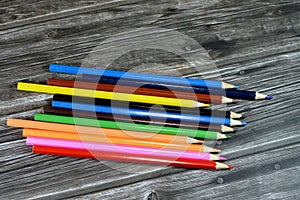 wood color pencils of different colors for painting isolated on wooden background, back to school concept, school supplies and