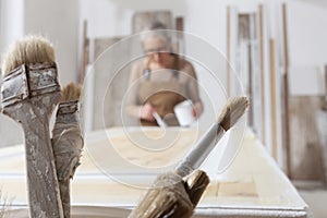 Wood crafts, woman artisan carpenter painting with brush and paint jar in her workshop, restoration, diy and handmade works