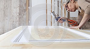 Wood crafts, woman artisan carpenter painting with spray gun paint white the door in her workshop, wearing overall and eyeglasses