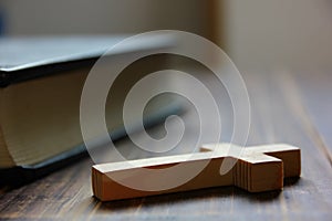 Wood cross with bible on brown wood floor