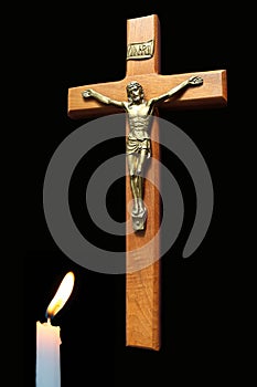 Wood cross with body of Christ with lit candle