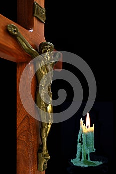 Wood cross with body of Christ and lit candle