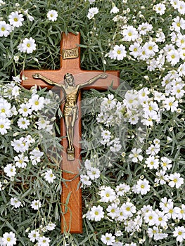 Wood cross with body of Jesus Christ placed on dainty white flowers