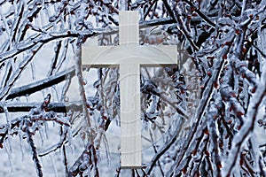 Wood cross hanging on ice covered tree branches
