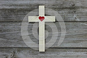 Wood cross with red heart on rugged wooden background