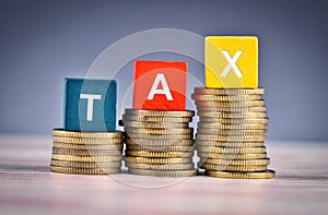 Wood cube with word TAX and stacking coin on wooden table