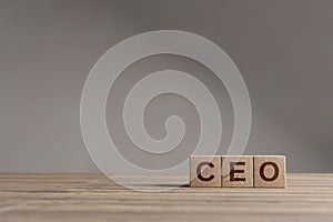 Wood cubes with acronym `CEO` - `Chief Executive Officer` on a beautiful wooden table, studio background. Business concept and