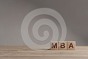 Wood cubes with acronym `MBA` - `Master of Business Administration` on a beautiful wooden table, studio background. Business