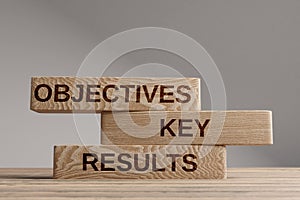 Wood cubes with acronym `OKR` - `Objectives and Key Results` on a beautiful wooden table, studio background. Business concept