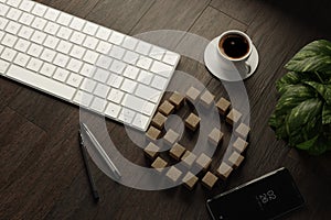 Wood cubes with illustration of happy emotion icon on desk with keyboard, coffee, pen, smartphone