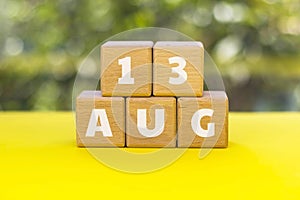 Wood cubes with text 13 AUG. 13th of August -International Lefthanders Day. Blurred natural green background. Summer