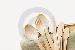 Wood cutlery spoons fork knife on beige linen cloth white wall background. Zero waste plastic free reusable biodegradable