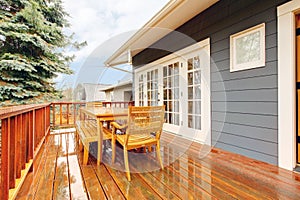 Wood deck with furniture and grey house.