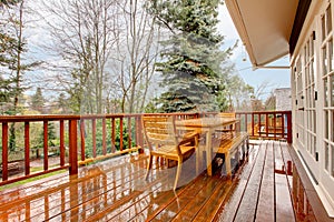 Wood deck with furniture and grey house.