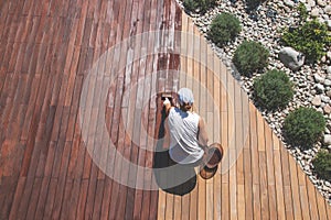 Wood deck renovation treatment, the person applying protective wood oil with a brush on ipe terrace photo