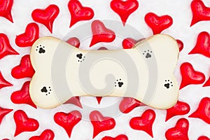 Wood dog bone with paw print with red hearts on white fabric background