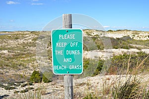 wood fence and sand dunes at the beach with please keep off sign