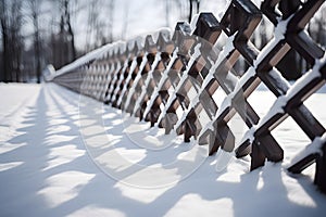 Wood fencing covered with snow in winter illuminated by the morning sun.