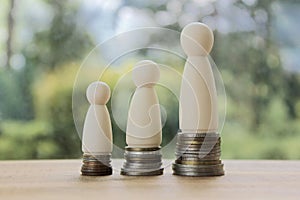 Wood figures of people standing on rows of rising coins.