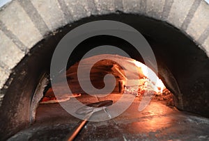 Wood-fired oven with italian pizza with cheese in pizzeria and shovel