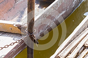 Wood Fishing Boat is Enchained by Iron Chain with Wood Boat Pole