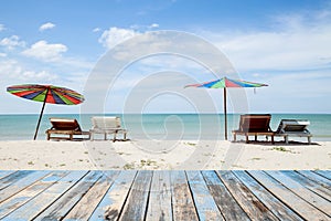 wood floor on beach chairs and colorful umbrella on tropical beach,blue sky and cloud background,beautiful scenery background.