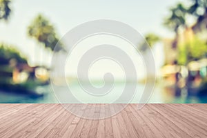 Wood floor with blur summer background tropical resort hotel with swimming pool water and palm tree